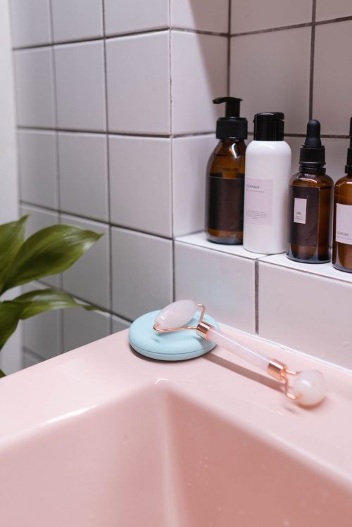 1970s-style pink bathroom sink with small white wall tiles in the background